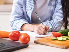 writing down a menu in the kitchen with food around