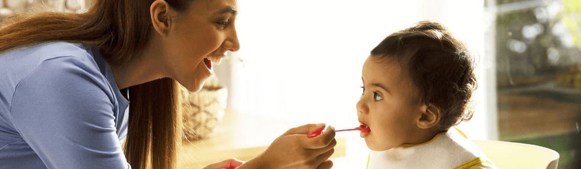 mum feeding baby cereal on spoon