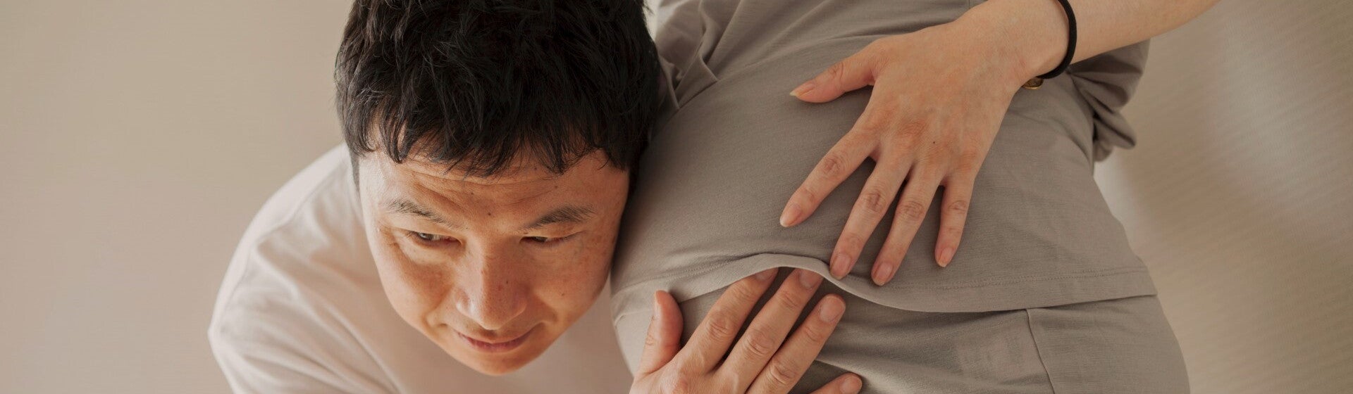man with ear against pregnant woman's stomach